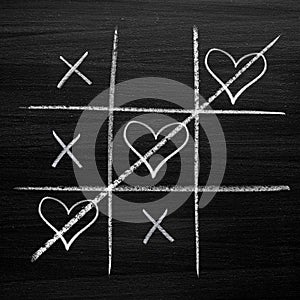 Tic tac toe game with chalk hearts, XO noughts and crosses Valentine`s Day style