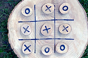 Tic tac toe game on a wooden board with wooden tac toe and crosses. winner strategy, winning skill, vision of an idea, ability to