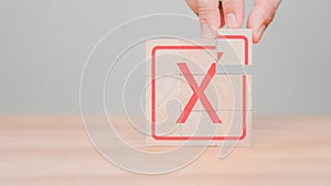 Tick and cross sign, approve and disapprove symbol. Hand placing wooden cube with red cross check mark sign.