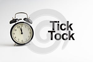 TICK TOCK inscription written and alarm clock on white background photo