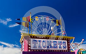 Ticket Booth and Rides at a Carnival Against Blue Sky