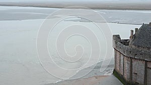 Tidal Wave and Mont Saint-Michel wall. Morning misty Sea View.