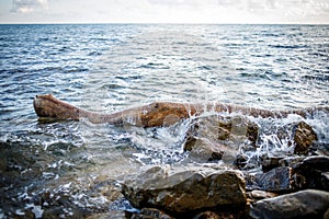 A tidal wave runs along large coastal stones with a crest.