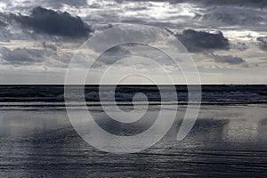 Tide is out, stormy clouds reflected on a wet beach