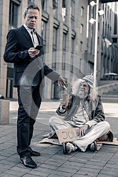 Tidy business man in costume putting money in coffee cup