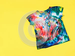 Tie dye pattern on a t-shirt on a yellow background. Flat lay.