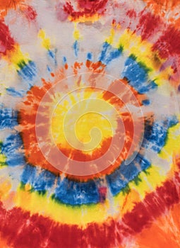 Tie dye style fabric background in yellow, blue, red and orange colors