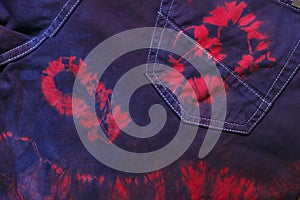 Tie dyed textile background, colored jeans.