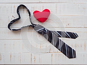 Tie forms a heart shaped and redheart on white wooden background