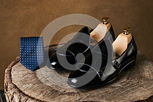 Tie and a Pair of man`s classic leather shoes on wooden stump