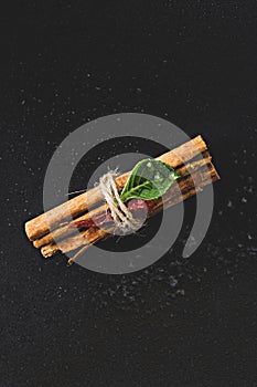 Tied bundle of cinnamon sticks on black background