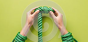 Tied hands holding a rope and trying to free themselves from the binding