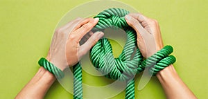 Tied hands holding a rope and trying to free themselves from the binding