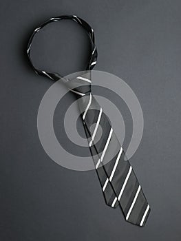 Tied men`s striped tie on a black background