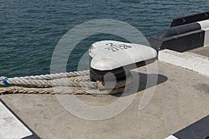 Tied rope on the knot around the mooring bollard. Nautical theme background