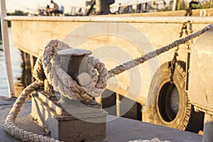 Tied rope knot on metallic bollard , seafaring port. Nautical ship moored in dock. Anchor rope in the port, ship mooring tool