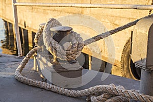 Tied rope knot on metallic bollard , seafaring port. Nautical ship moored in dock. Anchor rope in the port, ship mooring tool