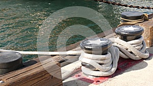 Tied rope knot on metallic bollard with stars, seafaring port of San Diego, California. Nautical ship moored in dock. Cable tie