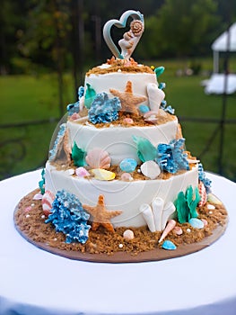 Tiered wedding cake with beach theme, adorned with starfish, seashells and coral