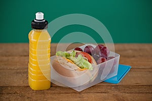 Tiffin box with fruit and sandwich on table