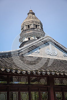 Tiger Hill Pagoda with blue sky in the background and building in foreground.