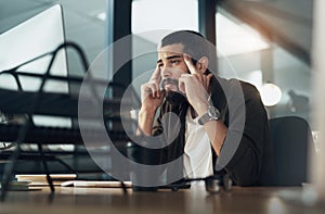 Tight deadlines come with big demands. a young businessman feeling stressed while working late at night in a modern