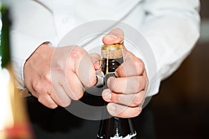 Tight hands opening a champagne bottle