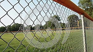 Tight shot of non professional baseball outfield shot through foul line fence