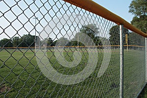 tight shot of non professional baseball outfield shot through foul line fence