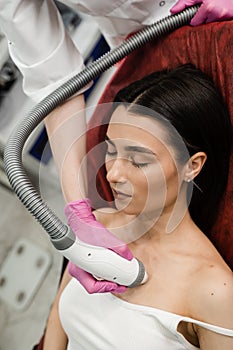 Tightening and rejuvenation of facial skin of girl at cosmetology procedure. Thermal or radio frequency hardware RF