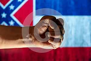 Tightly clenched male fist in front of state Mississippi flag. Concept of independence, freedom, and unity. Selective focus