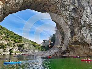 Tightrope walker girl between the natural arch of Vallon pont d`arc.