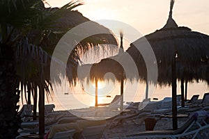 Tiki hut umbrellas, thatch. Sunrise view on beach in Tunisia. Sousse