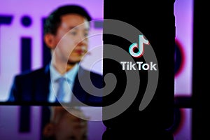 TikTok logo on screen and Tik Tok CEO Shou Zi Chew on blurred background