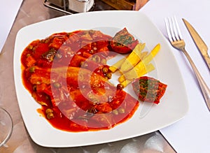 Tilapia fillet with vegetables, french fries and sun-dried tomatoes