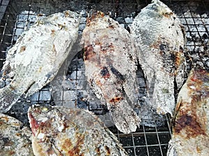 Tilapia fishes cover with salt Grilled on the black grates and charcoal stove