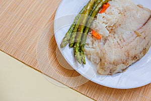 Tilapia sea fish with rice and green asparagus on a white thai. Healthy eating