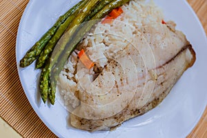 Tilapia sea fish with rice and green asparagus on a white thai. Healthy eating