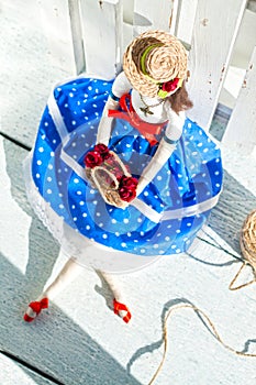 tilde doll in a blue skirt and a straw hat with a basket with fl