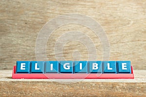 Tile letter on rack in word eligible on wood background