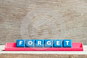 Tile letter on rack in word forget on wood background