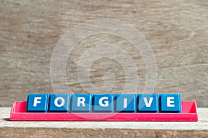 Tile letter on rack in word forgive on wood background