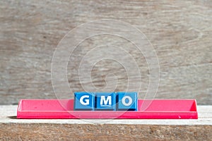 Tile letter on rack in word GMO abbreviation of Genetically Modified Organisms on wood background