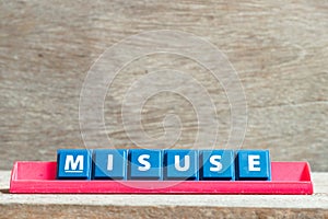 Tile letter on rack in word misuse on wood background