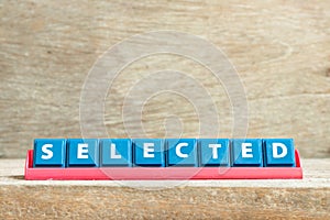 Tile letter on rack in word selected on wood background