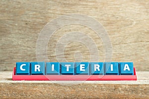 Tile letter on rack in word criteria on wood background