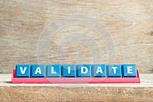 Tile letter on rack in word validate on wood background photo