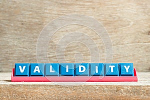 Tile letter on rack in word validity on wood background photo