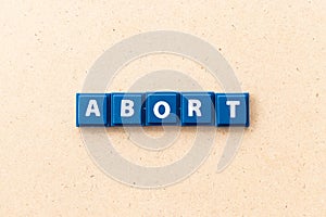 Tile letter in word abort on wood background