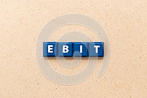 Tile letter in word EBIT Abbreviation of Earnings Before Interest and Taxes on wood background